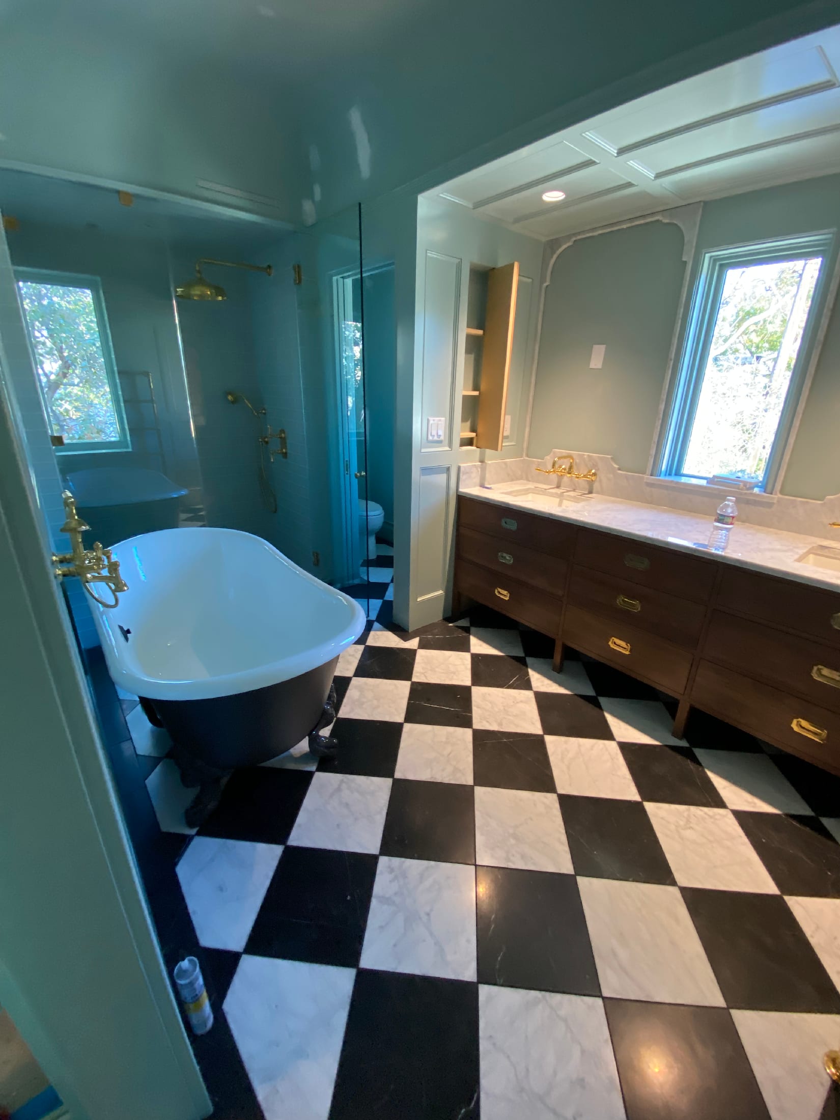 Sage-walled master bath with a clawfoot tub, walnut double vanity, and a black-and-white checkered marble floor.